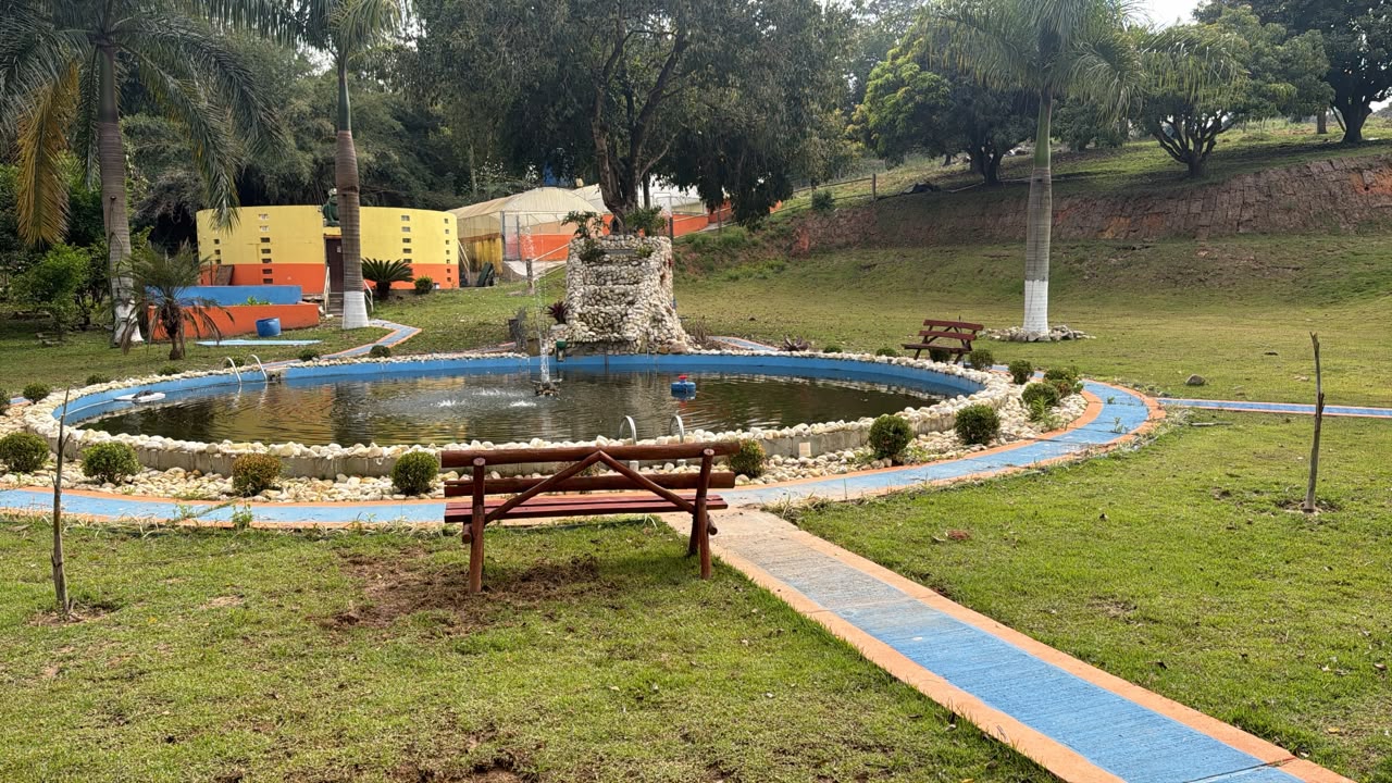 Lago com fonte de pedra e o ranário ao fundo, na Ranamari